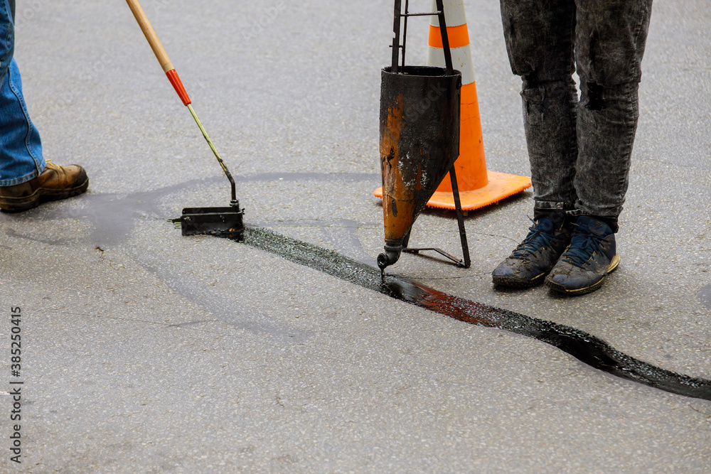Sealing joint crack in asphalt road surface restoration work.